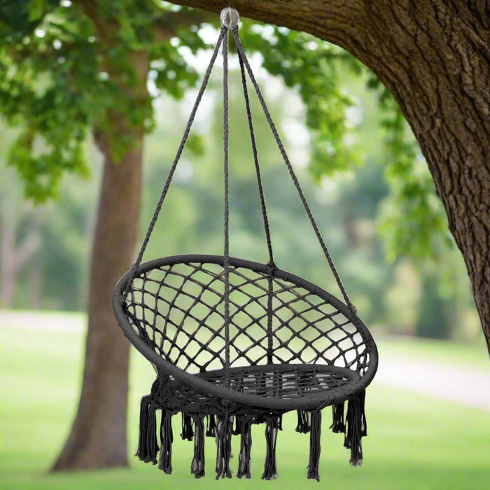 Anthracite hammock swing chair with tassels hanging from a tree outdoors