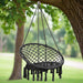Anthracite hammock swing chair with tassels hanging from a tree outdoors