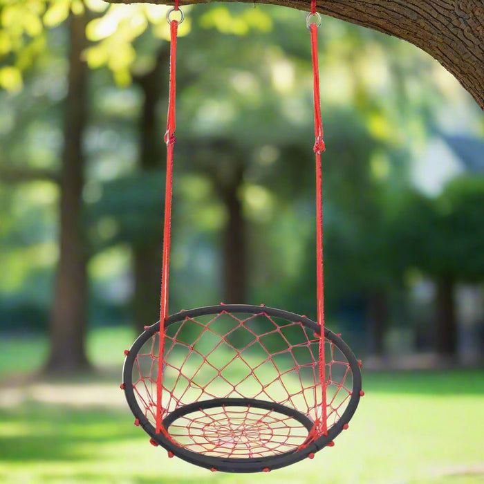 Red and black web swing chair with adjustable ropes hanging from a tree outdoors