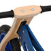 Close-up of blue and black balance bike with plywood frame, adjustable handlebar and seat