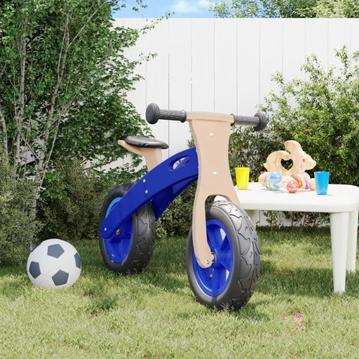 Blue and black balance bike with plywood frame in a backyard near a soccer ball and toy table