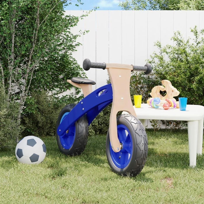 Blue and black balance bike with plywood frame in a backyard near a soccer ball and toy table