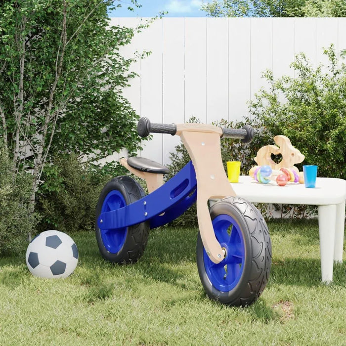 Blue and black balance bike with plywood frame and adjustable seat in a grassy backyard