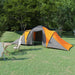 Grey and orange 6 person camping tent set up on grassy field with trees in background