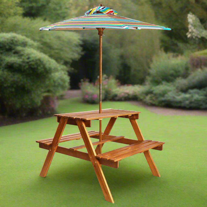 Children's wooden picnic table with colorful parasol on green lawn in garden