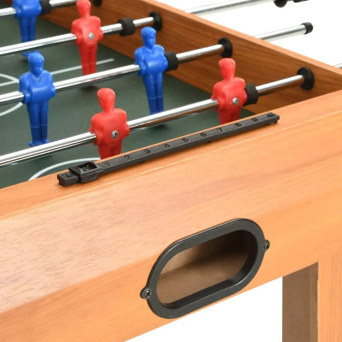Close-up of maple wood foosball table with red and blue players, score counter visible.