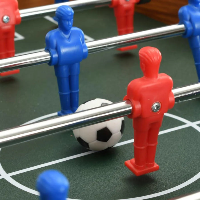 Foosball table close-up with red and blue players and a soccer ball on green field
