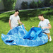 Two people assembling a blue inflatable octopus pool on grass outdoors