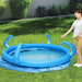 Woman filling blue inflatable octopus pool with sprayer tentacles on green lawn outdoors