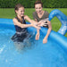 Two people playing in an inflatable octopus pool with sprayer tentacle outdoors