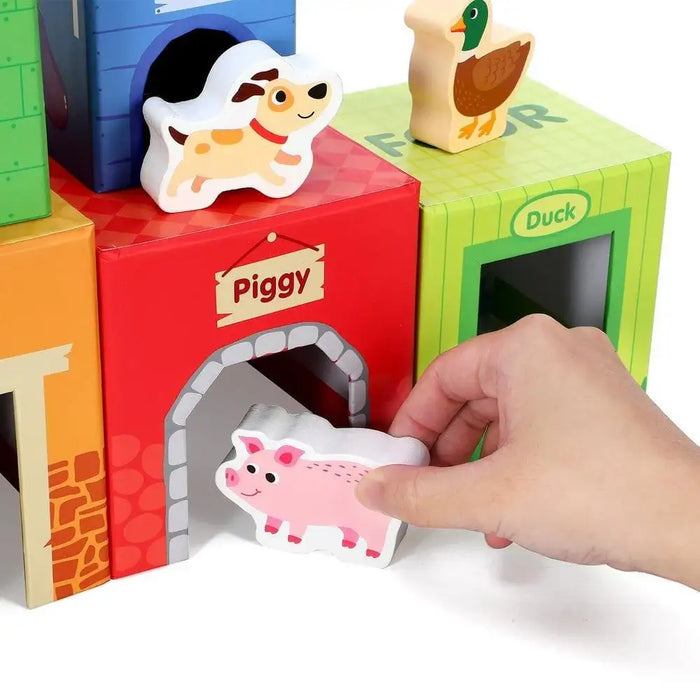 Hand placing pig block in colorful farm animal stacking cubes toy with dog and duck pieces