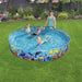 Kids and adult in Fill-n-Fun Odyssey pool with coral reef design on green lawn