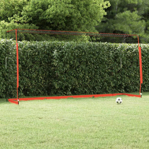 Foldable football goal with black net and red frame on grass, soccer ball nearby, outdoor setting