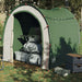 Green taffeta storage tent with gear bags outdoors in a grassy, wooded area