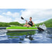 Woman paddling green Hydro-Force inflatable kayak on lake with lush hills in background
