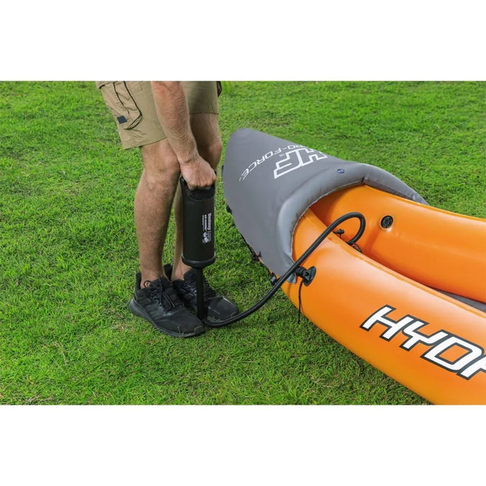 Person inflating orange Hydro-Force inflatable kayak with hand pump on grass