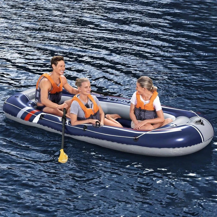 Three people in orange life vests on a blue inflatable boat on water