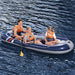 Three people in orange life vests on a blue inflatable boat on water