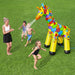 Kids playing with jumbo inflatable giraffe sprinkler water toy on green grass outdoors