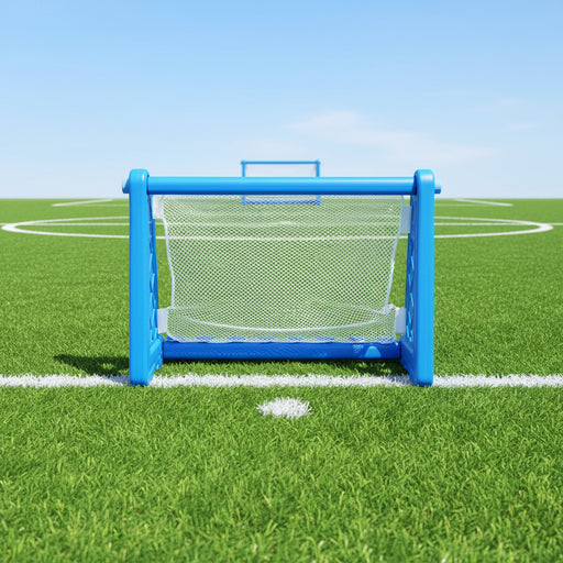 Blue plastic kids football goal with net on green soccer field outdoors
