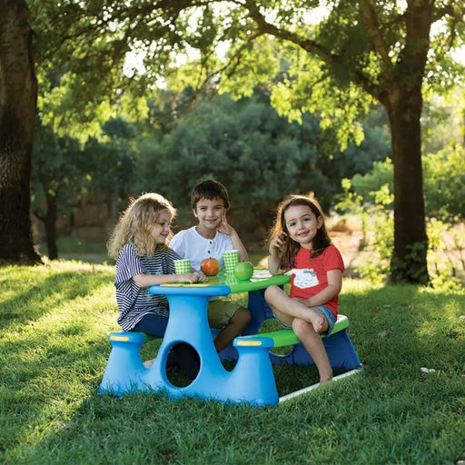 Kids sitting at a blue and green picnic bench in a sunny outdoor park setting