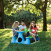 Kids sitting at a blue and green picnic bench in a sunny outdoor park setting