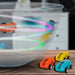 Colorful magic doodle cars with LED lights racing in a clear bowl on a wooden surface