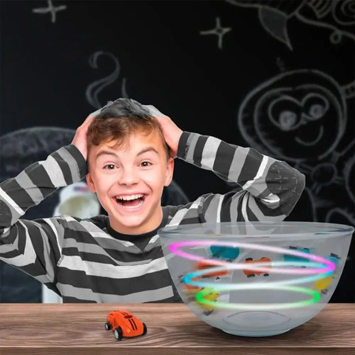 Smiling boy with orange magic doodle car, LED line following racing toy, chalkboard background