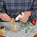 Mini glue gun used for crafting with glitter gold flowers and artificial leaves on table