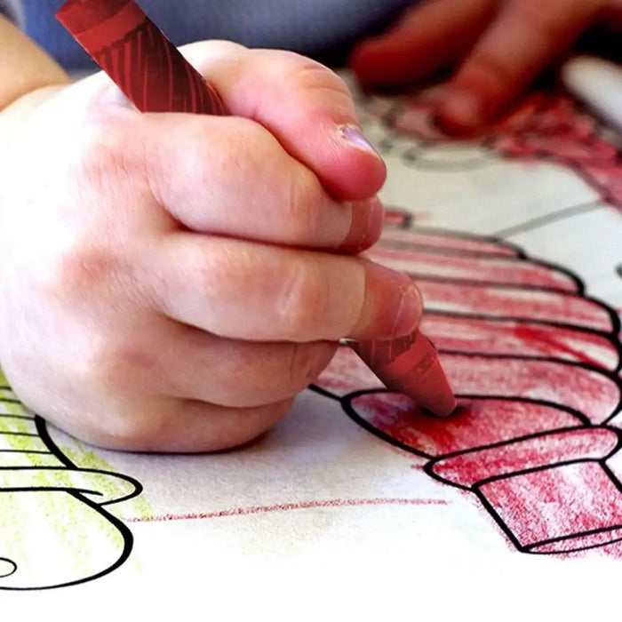 Child coloring with red wax crayon on outlined drawing, close-up hand view