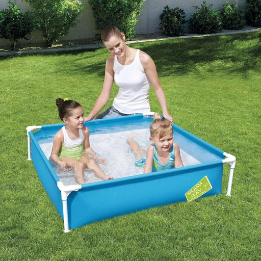 Parent with two children in a blue metal-frame kiddie pool on green grass outdoors
