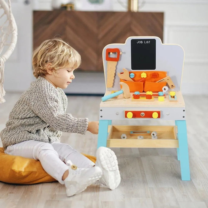 Toddler playing with wooden workbench toy set with tools indoors