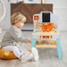 Toddler playing with wooden workbench toy set with tools indoors