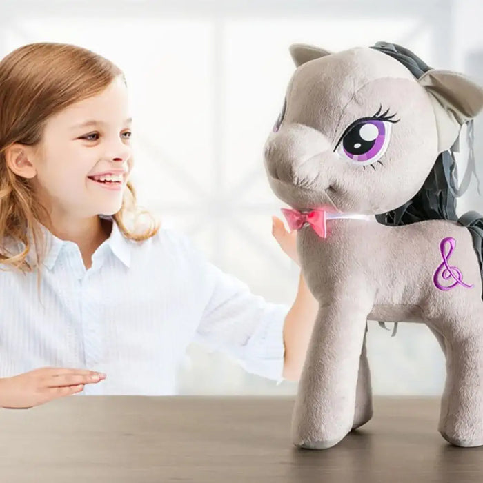 Smiling child with large My Little Pony plush toy, gray with purple eyes and a treble clef symbol.