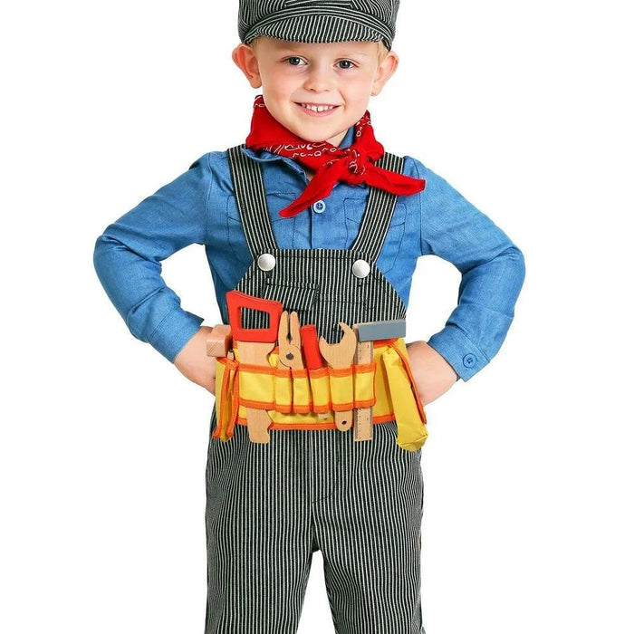 Smiling child in overalls wearing striped hat, red bandana, and wooden toy tool belt set