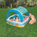 Kids in an inflatable pool with canopy outdoors, featuring ocean-themed design, summer fun