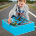 Child playing with foldable blue toy garage and road playmat set featuring cars and traffic light