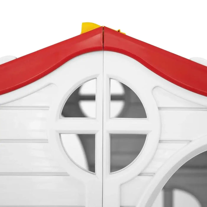 Close-up of white plastic kids’ playhouse with red roof and round window detail.