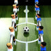 Professional black football table with green pitch, white and blue player figures and soccer ball