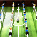 Professional brown foosball table with green pitch, blue and white player figures, soccer ball at center