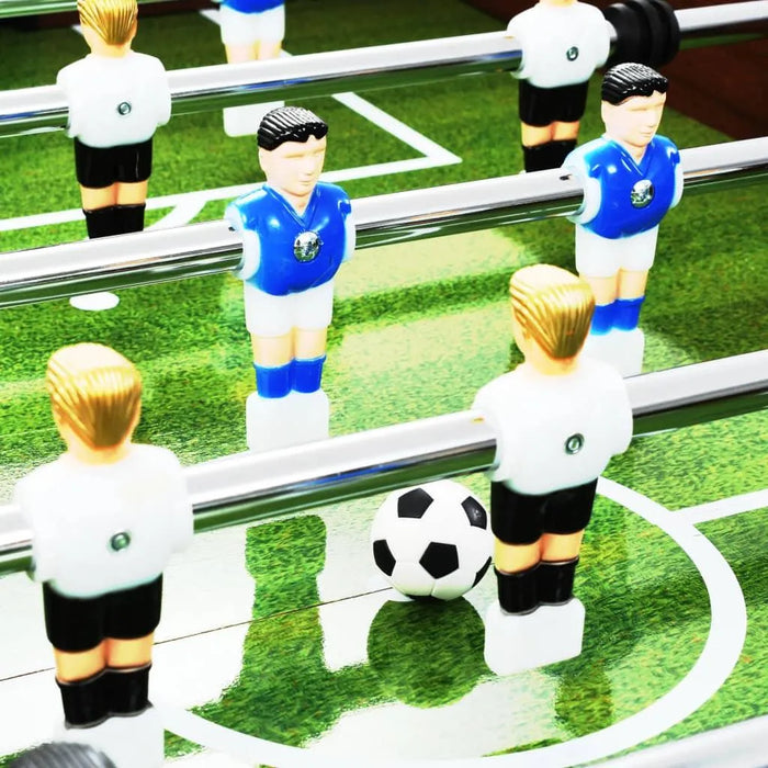 Close-up of foosball table match on green field, black-and-white soccer ball, blue and white players