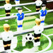 Close-up of foosball table match on green field, black-and-white soccer ball, blue and white players