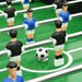 Close-up of black and blue team foosball table players with soccer ball on green field