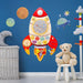 Space-themed rocket-shaped wooden activity board on blue wall in kids room with teddy bear