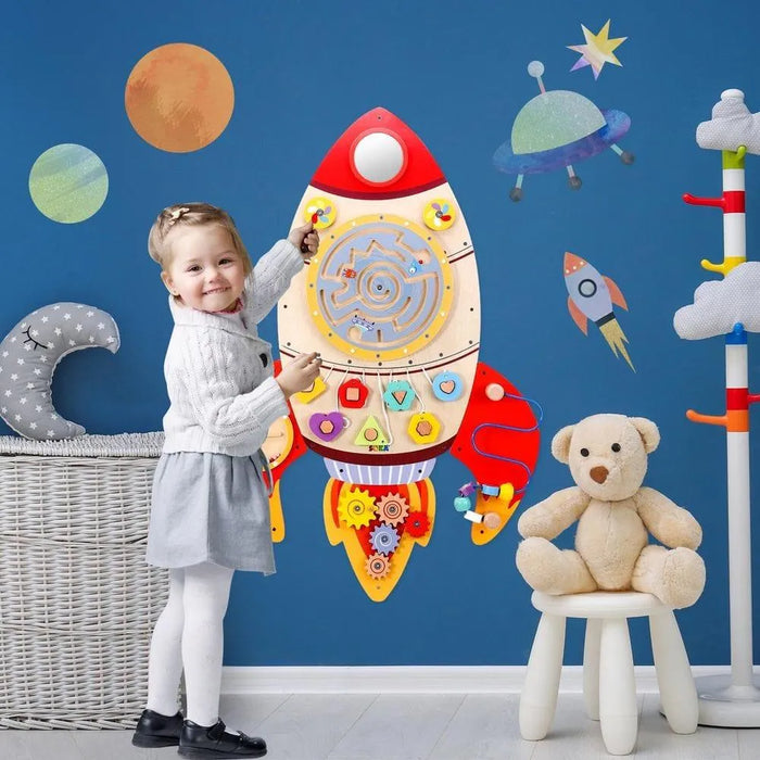 Girl playing with rocket-shaped wooden space activity board on blue wall with planets