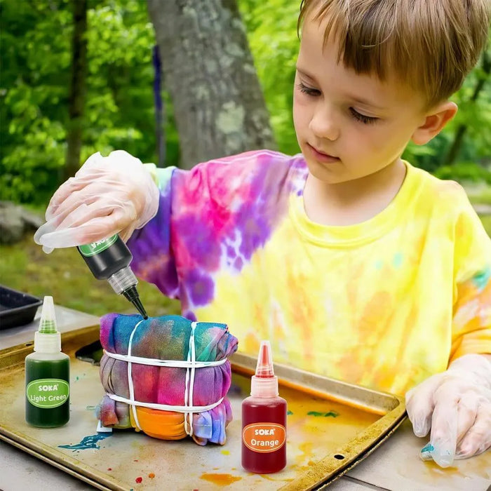 Child making tie-dye shirt outdoors with tie-dye kit, SOKA dyes, and protective gloves