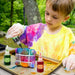 Child making tie-dye shirt outdoors with tie-dye kit, SOKA dyes, and protective gloves