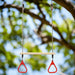 Trapeze swing bar with red rings and pinewood bar hanging outdoors on a tree branch