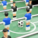 Close-up of foosball table game with blue and black player figures and soccer ball on green field
