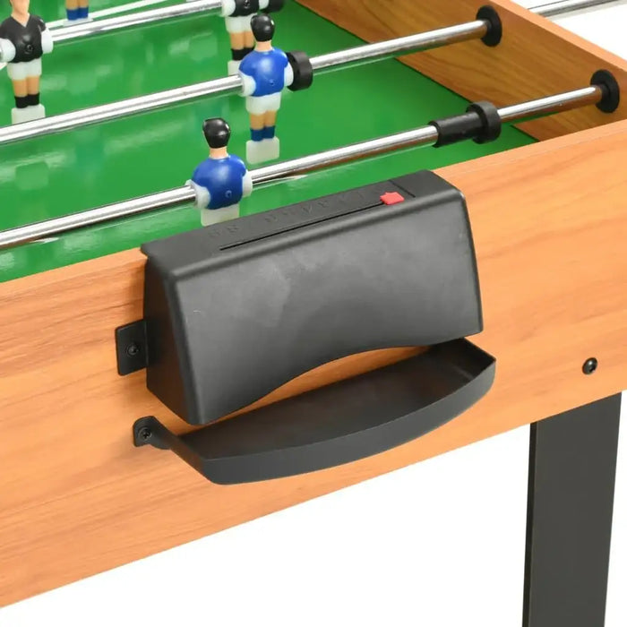 Close-up of wooden foosball table with green field, plastic players, and black handle
